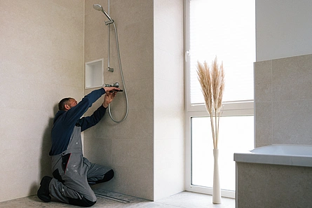 Illustration - Ihr Experte für schönes Wohnen - Handwerker installiert Duscharmatur im Badezimmer.